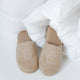 bathslippers in color latte with DOUXE logo, laying in a duvet